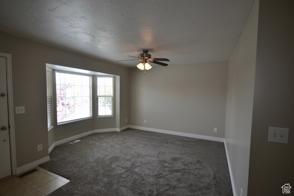 Spare room featuring ceiling fan, carpet flooring, and baseboards