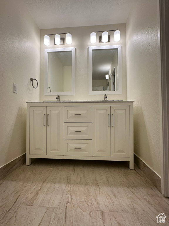 Full bathroom featuring double vanity and baseboards