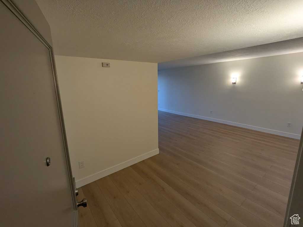 Empty room with wood finished floors, baseboards, and a textured ceiling