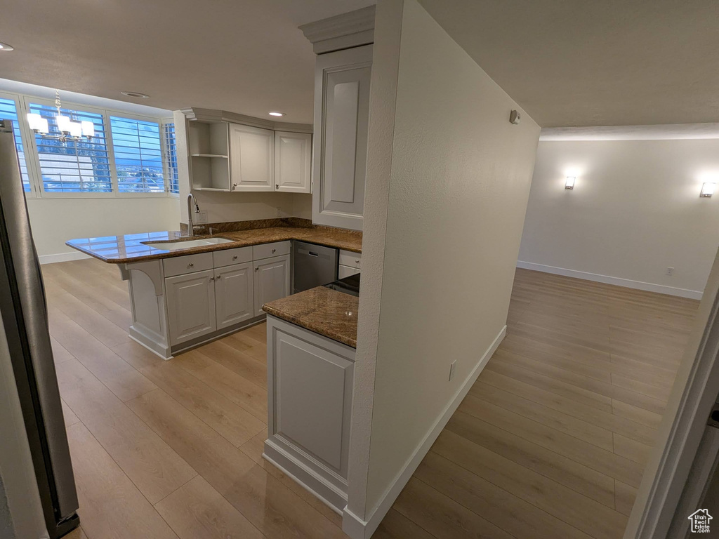 Kitchen with baseboards, open shelves, appliances with stainless steel finishes, a sink, and light wood-style floors