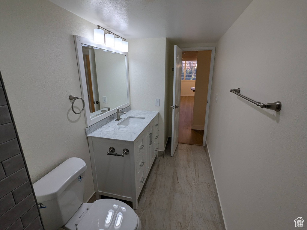 Bathroom with toilet, marble look tile flooring, and vanity