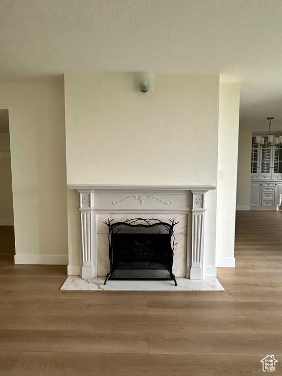 Detailed view of a fireplace with flush hearth, wood finished floors, baseboards, and a textured ceiling