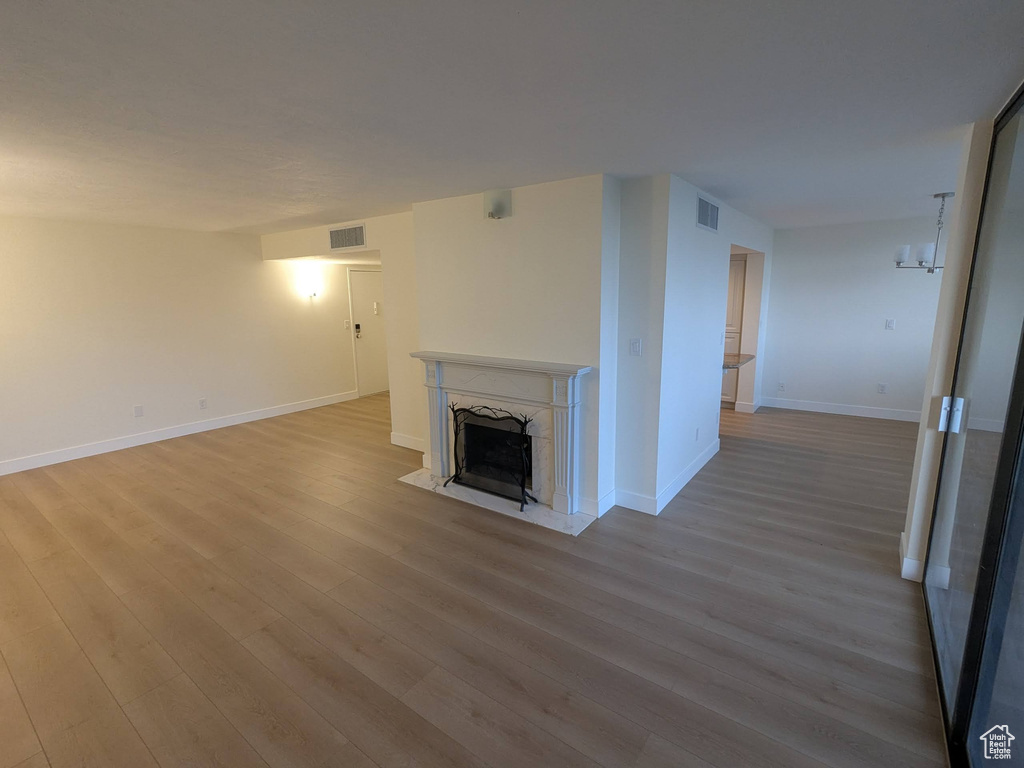 Unfurnished living room with wood finished floors, a high end fireplace, and baseboards