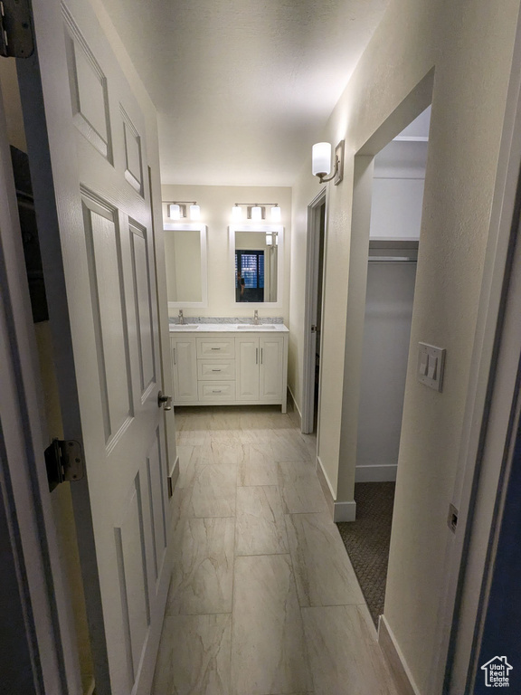Full bathroom featuring marble finish floors, double vanity, baseboards, and a spacious closet