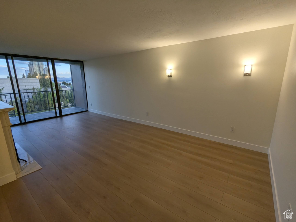 Spare room with baseboards, hardwood / wood-style floors, and expansive windows