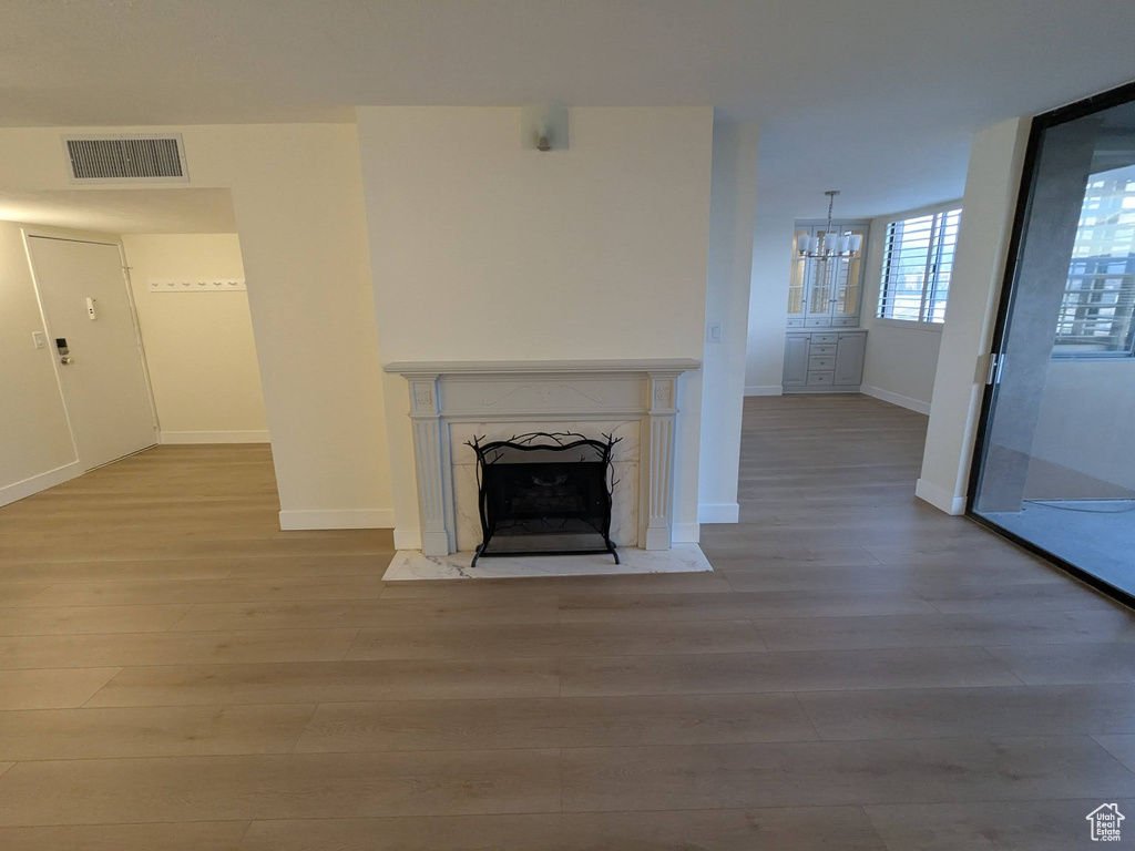 Unfurnished living room featuring wood finished floors, a chandelier, a premium fireplace, and baseboards