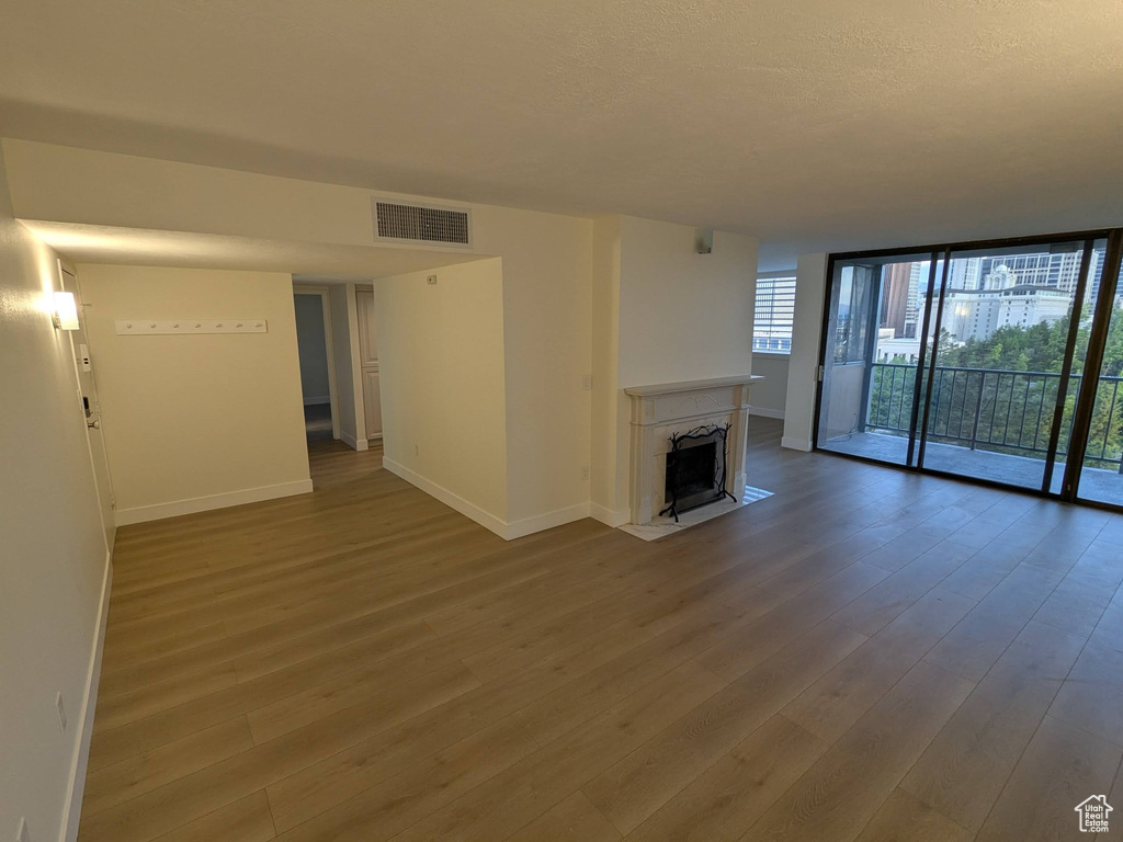 Unfurnished living room featuring baseboards, wood finished floors, floor to ceiling windows, and a fireplace
