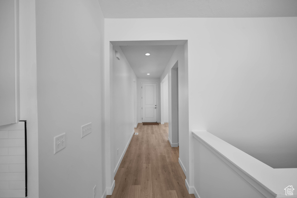 Corridor with light wood-style floors, recessed lighting, baseboards, and an upstairs landing