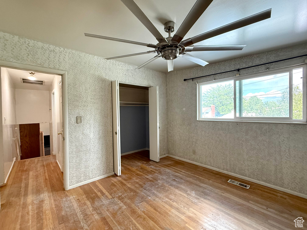 Unfurnished bedroom featuring wood-type flooring, baseboards, a closet, and a ceiling fan