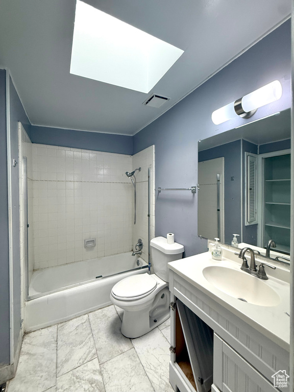 Bathroom featuring a skylight, vanity,  shower combination, toilet, and marble look tile flooring