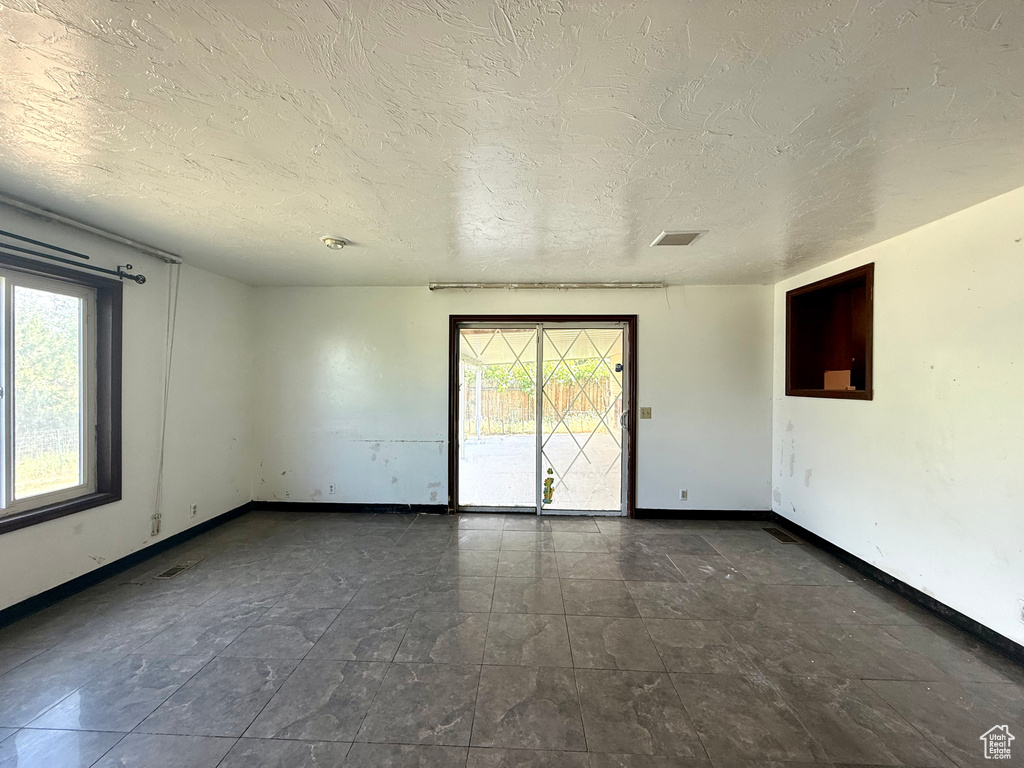 Empty room featuring plenty of natural light, baseboards, and a textured ceiling