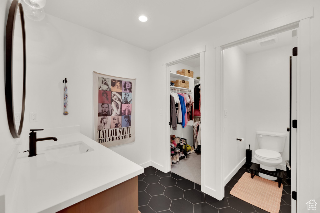 Bathroom with vanity, toilet, recessed lighting, a spacious closet, and tile patterned flooring