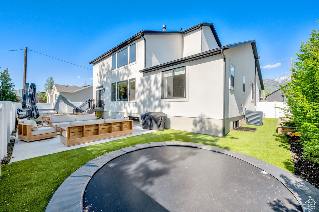 Back of property featuring an outdoor hangout area, stucco siding, a patio, and a trampoline