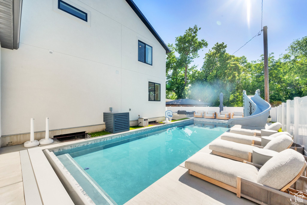 View of pool with a water slide and a fenced backyard