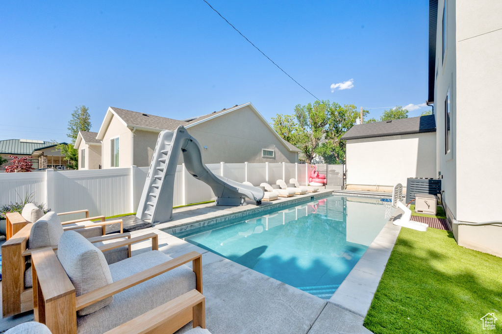 View of pool featuring a water slide and a fenced backyard