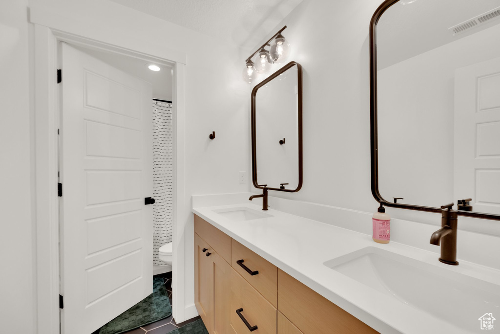 Bathroom featuring double vanity, toilet, a shower with curtain, and tile patterned floors