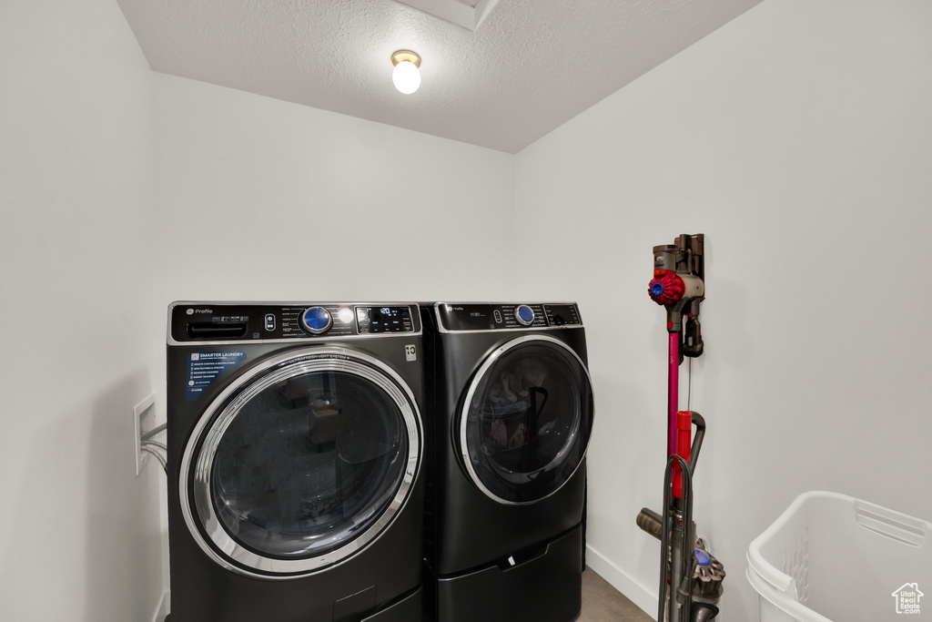 Laundry room featuring washing machine and dryer, baseboards, and a textured ceiling