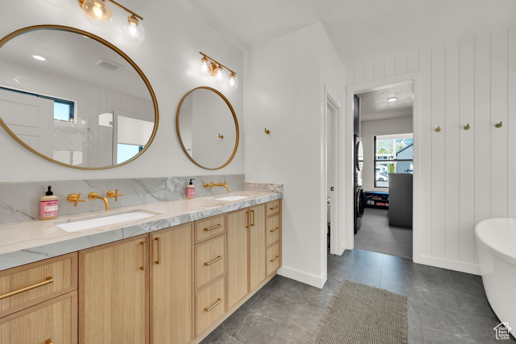 Bathroom featuring double vanity, a freestanding bath, a shower, baseboards, and decorative backsplash