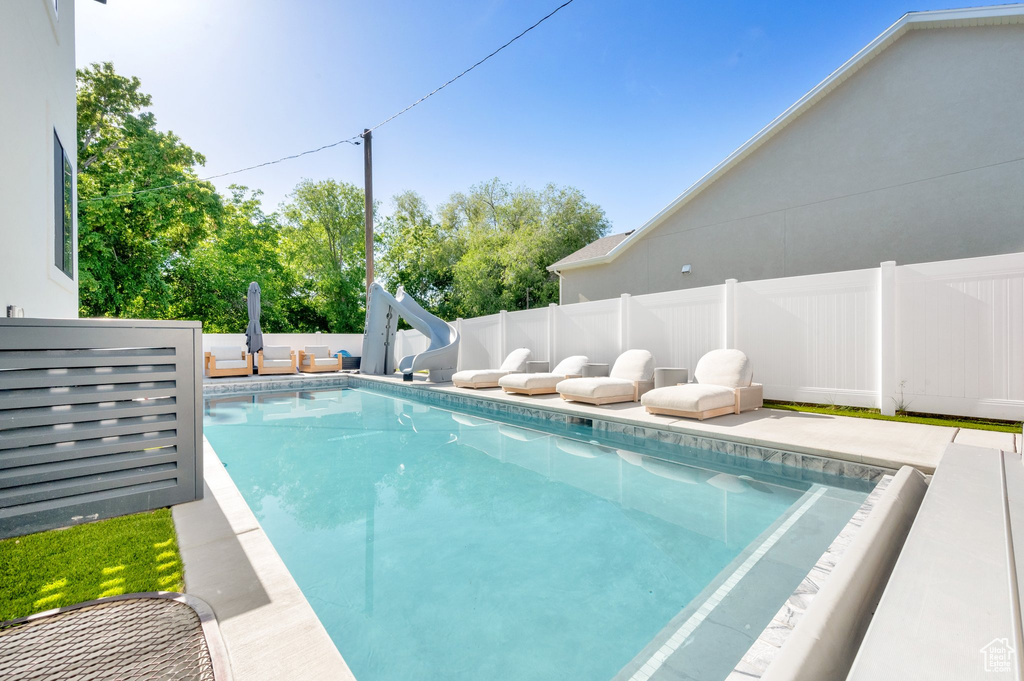 View of swimming pool featuring a water slide and a fenced backyard