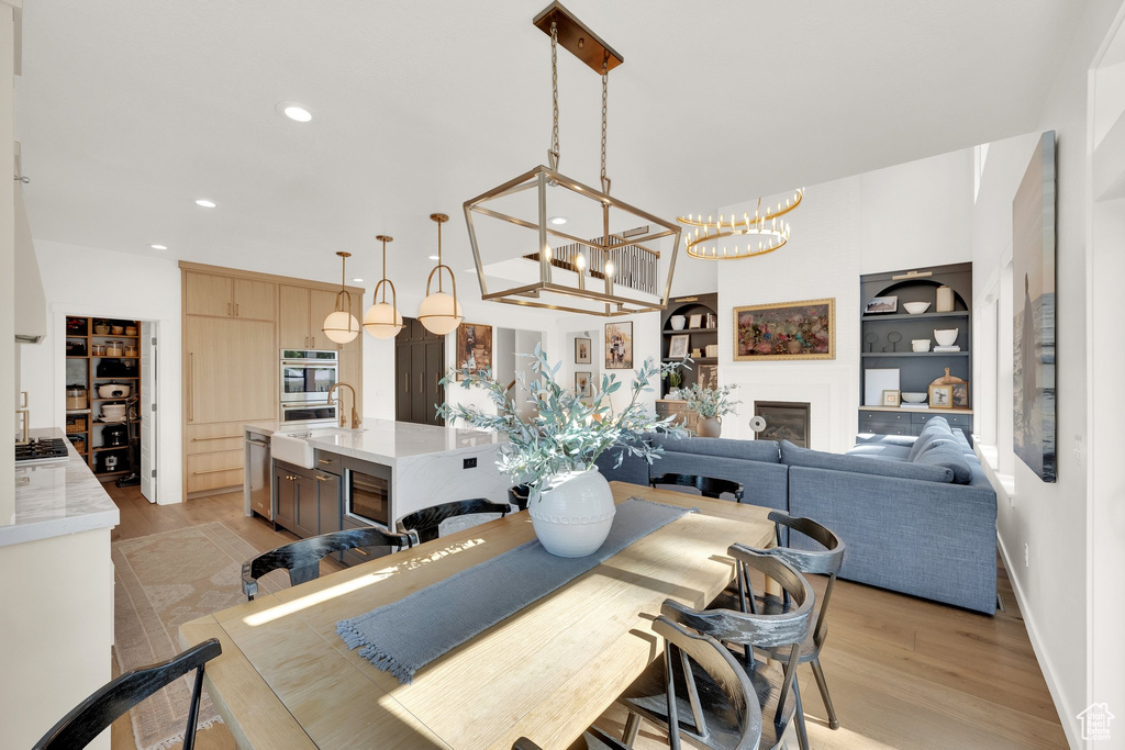 Dining room with recessed lighting, light wood-style flooring, a chandelier, baseboards, and built in features