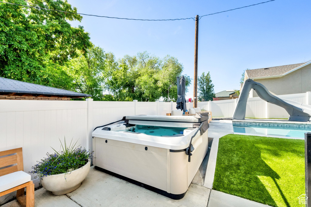 View of pool with a hot tub and a water slide