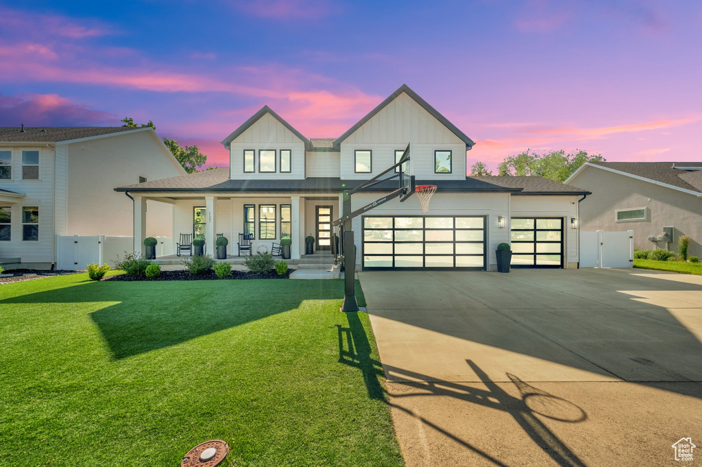 View of front facade with covered porch, board and batten siding, concrete driveway, a garage, and a gate