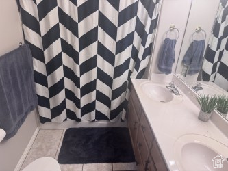 Full bath featuring double vanity, curtained shower, toilet, and tile patterned floors