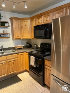 Kitchen with black appliances, a sink, light tile patterned flooring, open shelves, and dark countertops