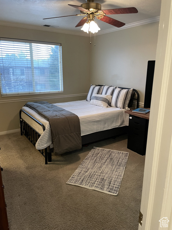 Carpeted bedroom with crown molding, baseboards, and ceiling fan