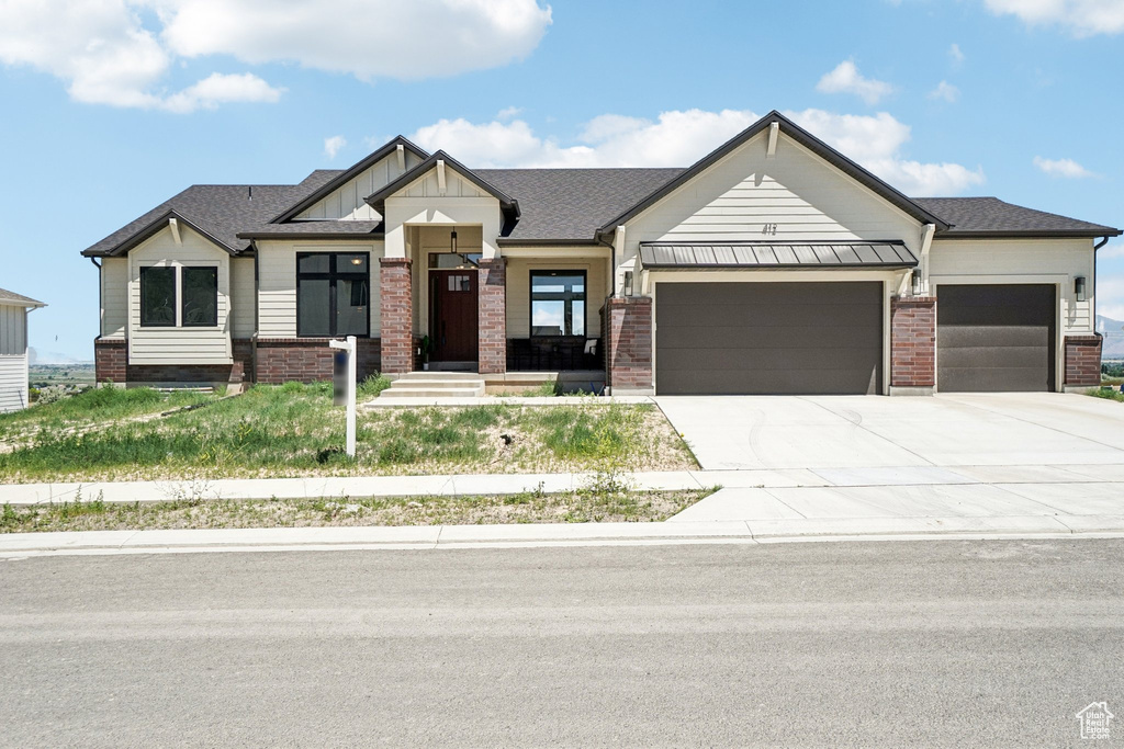 View of front of home featuring a garage, concrete driveway, and brick siding