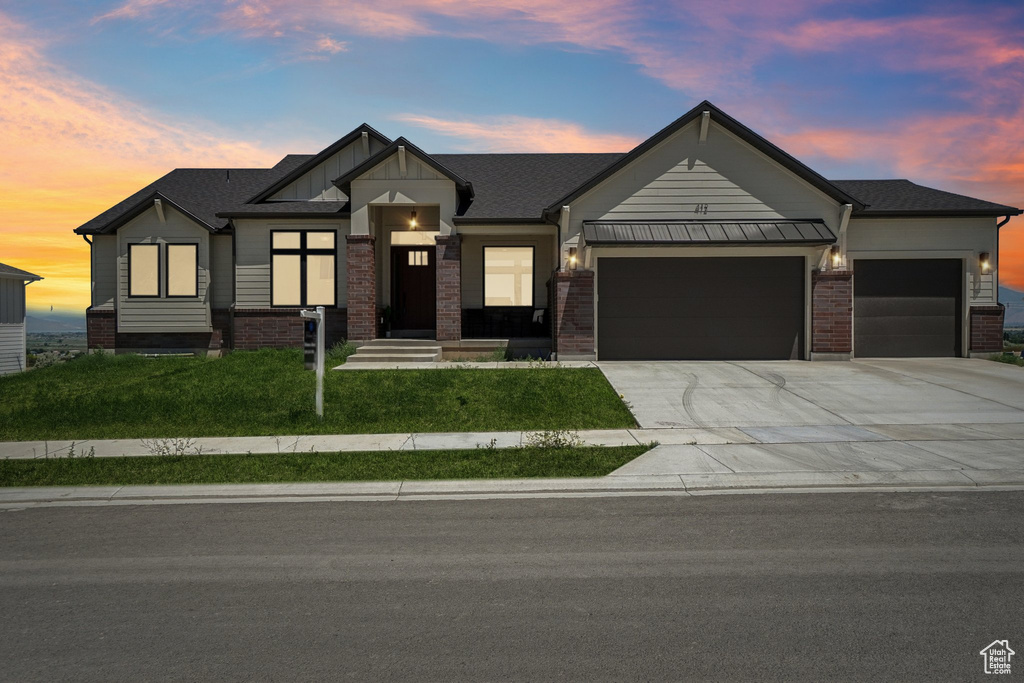 View of front of home featuring an attached garage, concrete driveway, a front lawn, and brick siding