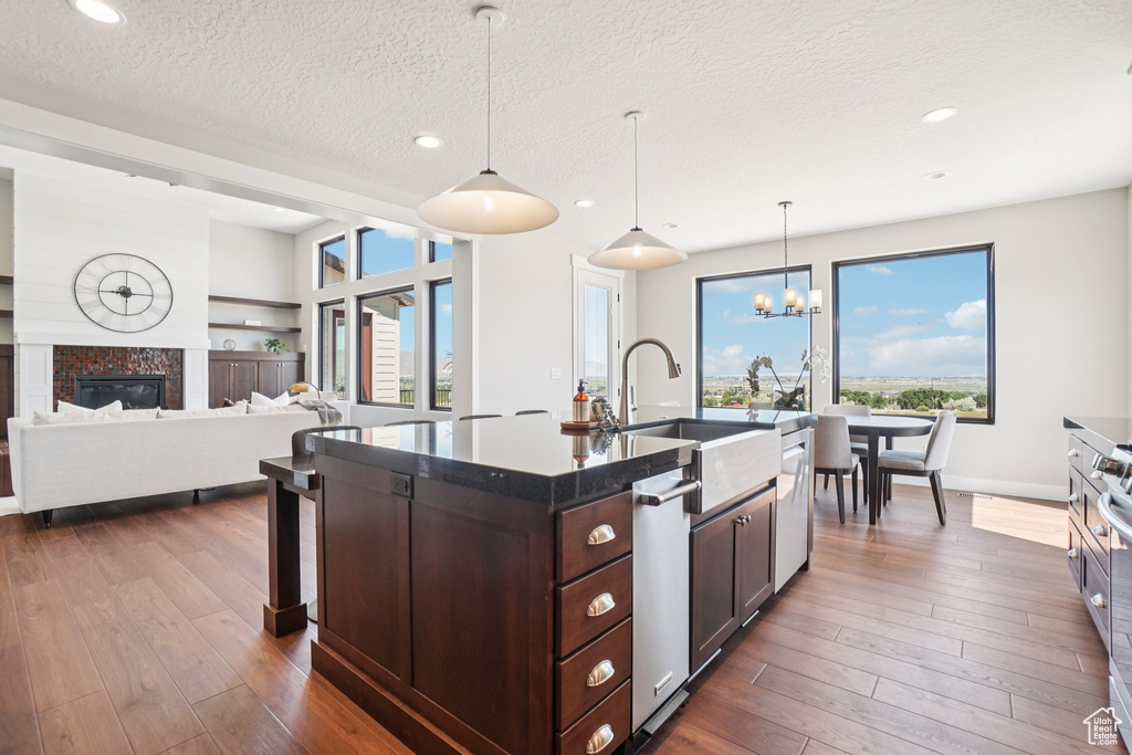Kitchen featuring a sink, stainless steel dishwasher, a chandelier, dark wood finished floors, and a textured ceiling