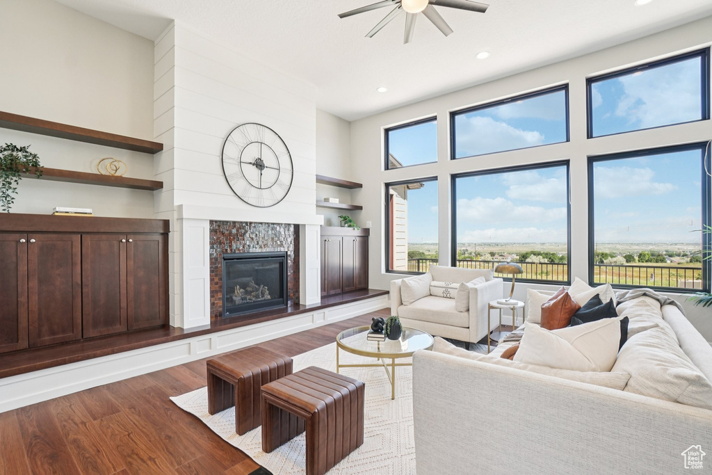 Living area with ceiling fan, wood finished floors, a fireplace, recessed lighting, and a towering ceiling