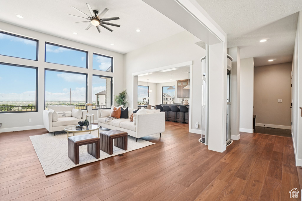Living room with ceiling fan, wood finished floors, healthy amount of natural light, baseboards, and recessed lighting