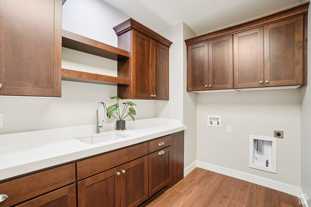 Washroom featuring hookup for an electric dryer, cabinet space, washer hookup, light wood-style floors, and baseboards