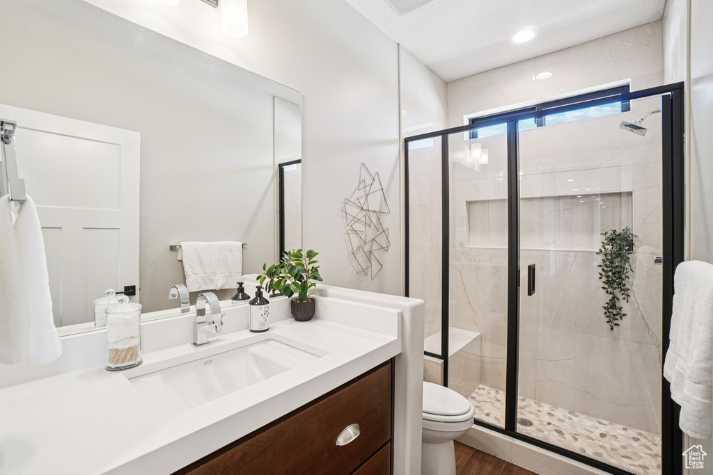 Full bathroom with toilet, vanity, a shower stall, and wood finished floors