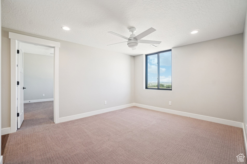 Spare room featuring ceiling fan, light colored carpet, a textured ceiling, baseboards, and recessed lighting