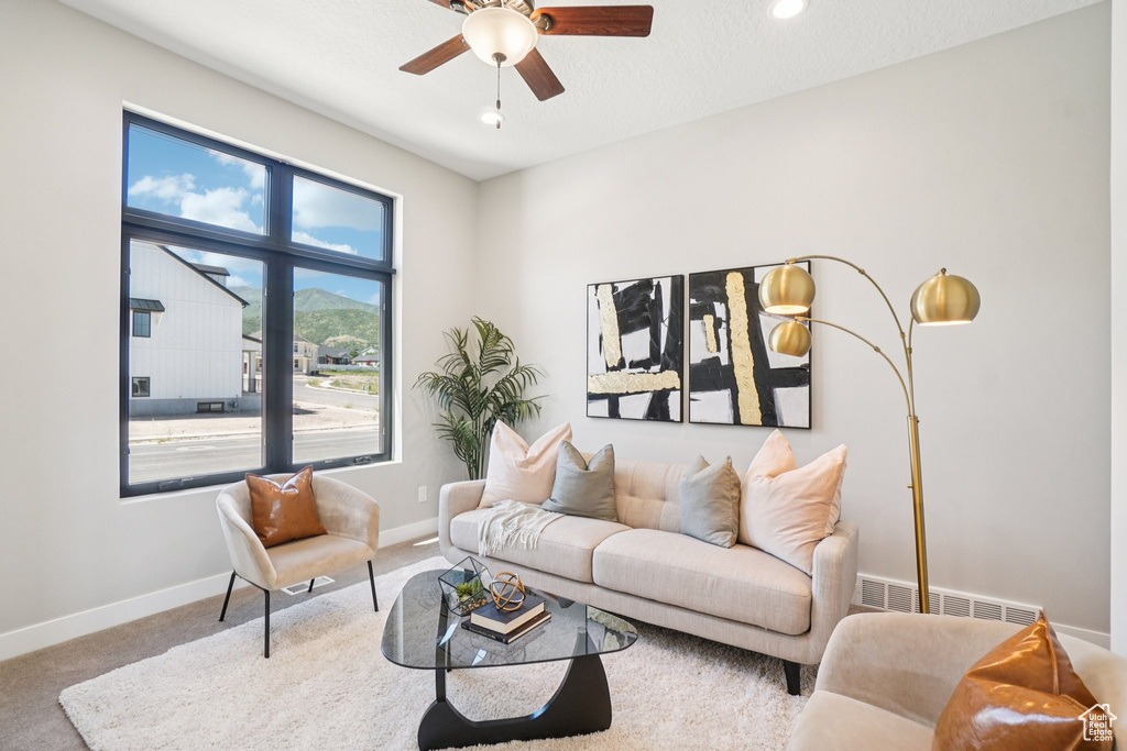 Carpeted living room featuring a ceiling fan, baseboards, and recessed lighting