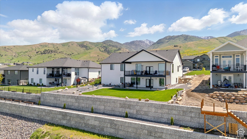 Back of property featuring a residential view, a patio area, a mountain view, and a balcony