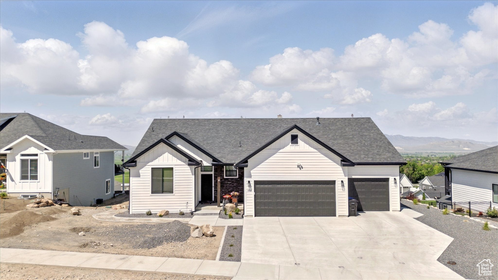 View of front of home with board and batten siding, an attached garage, concrete driveway, and roof with shingles