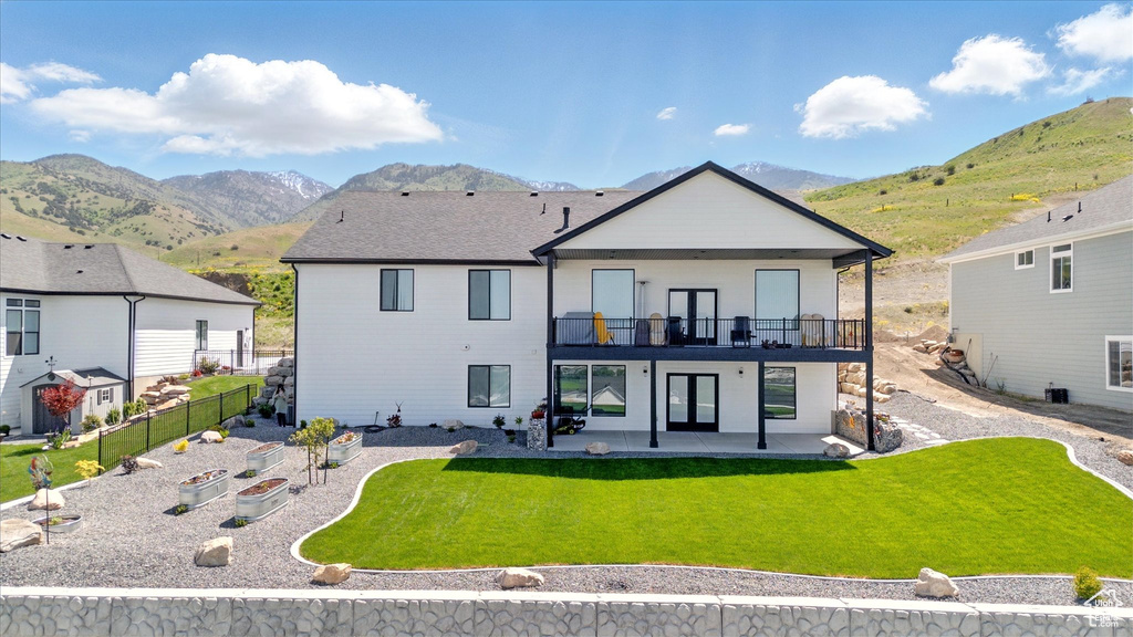 Back of house featuring a patio area, a mountain view, a balcony, and a vegetable garden