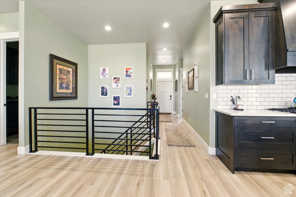 Hall with an upstairs landing, light wood-type flooring, baseboards, and recessed lighting