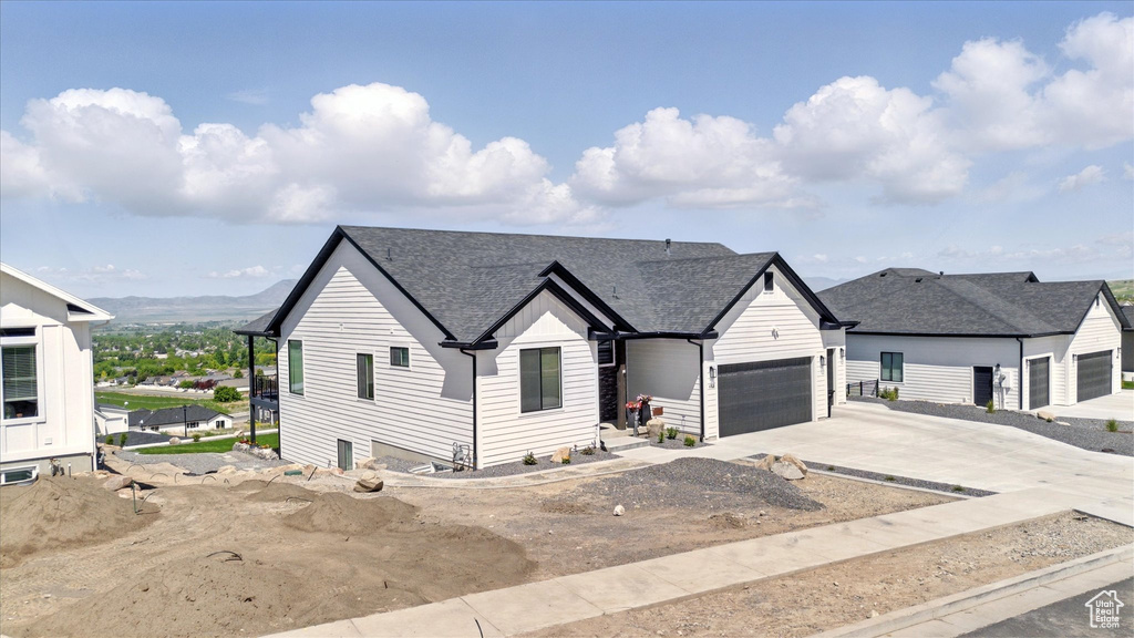 View of front of property with concrete driveway, a garage, and roof with shingles