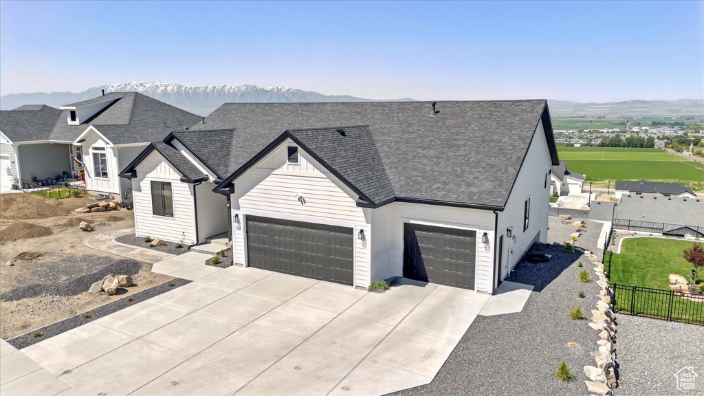 View of front of home featuring driveway, a shingled roof, a mountain view, and a garage