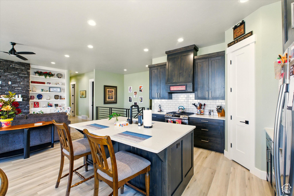 Kitchen with appliances with stainless steel finishes, a kitchen island, light countertops, a ceiling fan, and recessed lighting