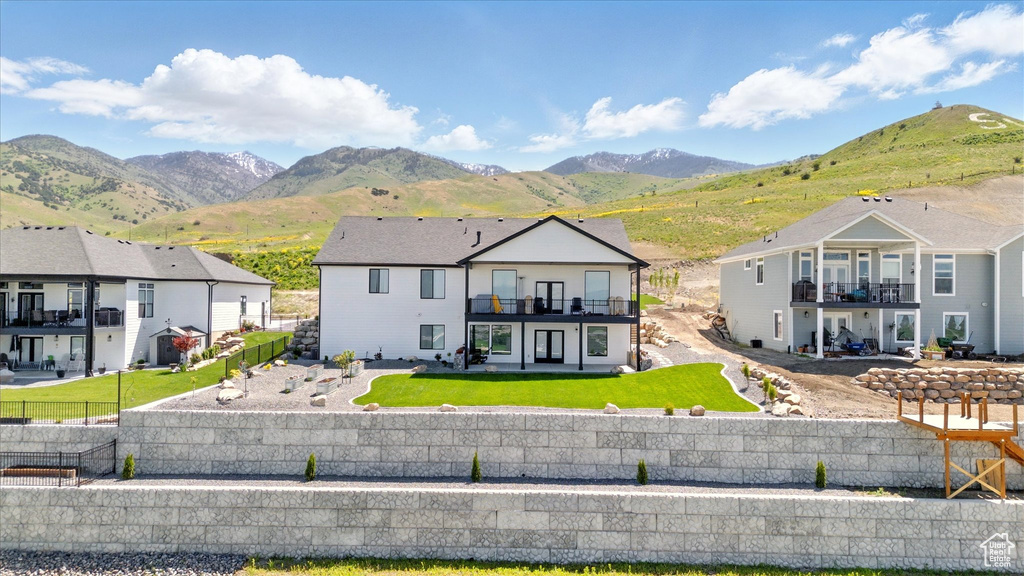 View of front of home featuring a balcony, a mountain view, a patio area, and a residential view