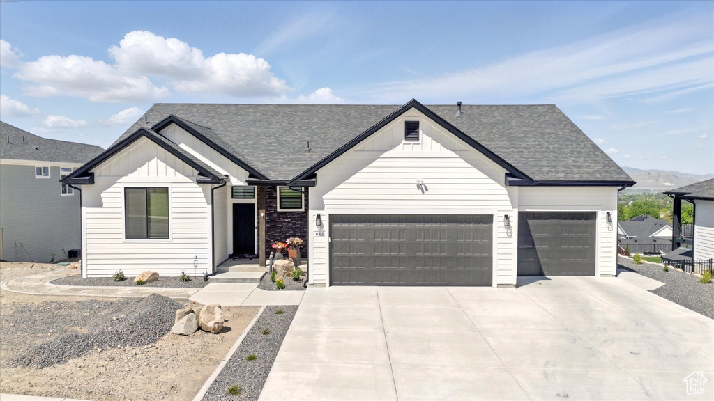 Modern farmhouse style home featuring board and batten siding, a garage, a shingled roof, and concrete driveway
