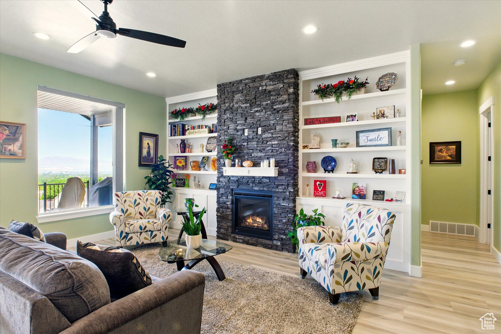 Living area with a ceiling fan, baseboards, wood finished floors, a stone fireplace, and recessed lighting