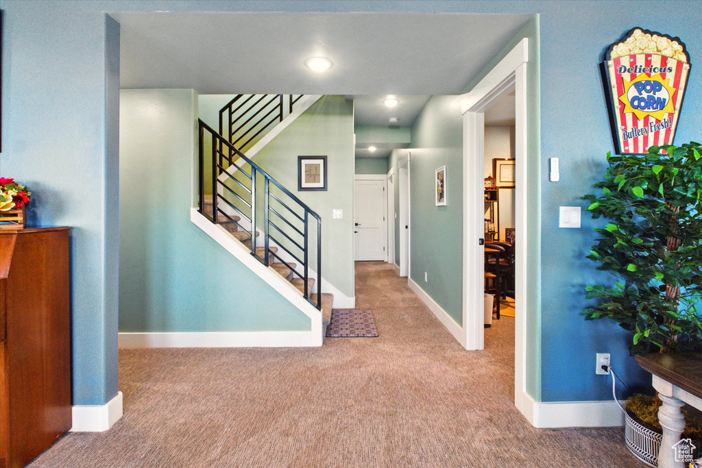Carpeted foyer featuring stairs and baseboards