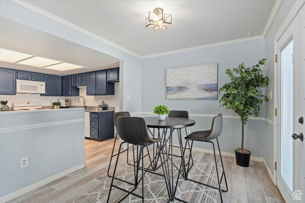 Dining space featuring light wood finished floors, baseboards, and crown molding